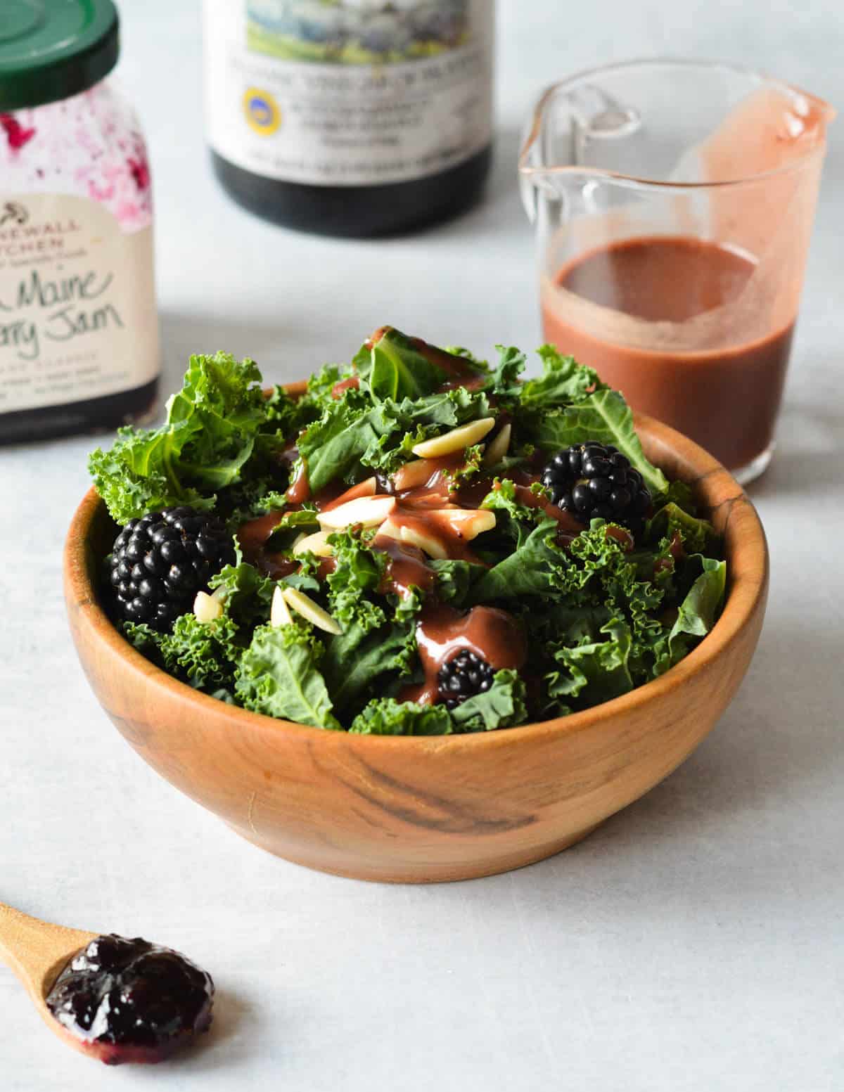 kale salad with blackberries, almonds, and balsamic dressing on top.