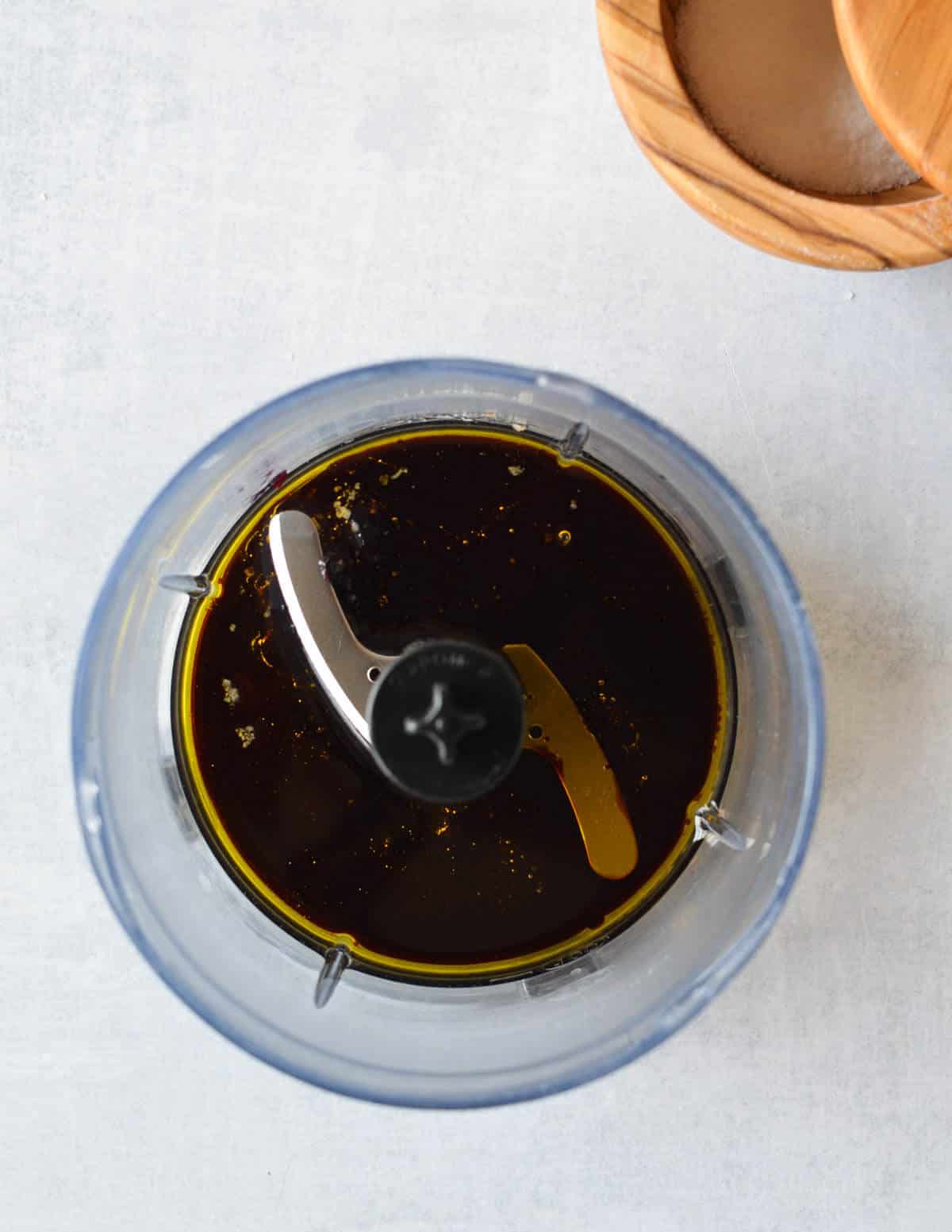 a food processor with olive oil, balsamic, and jam in it.