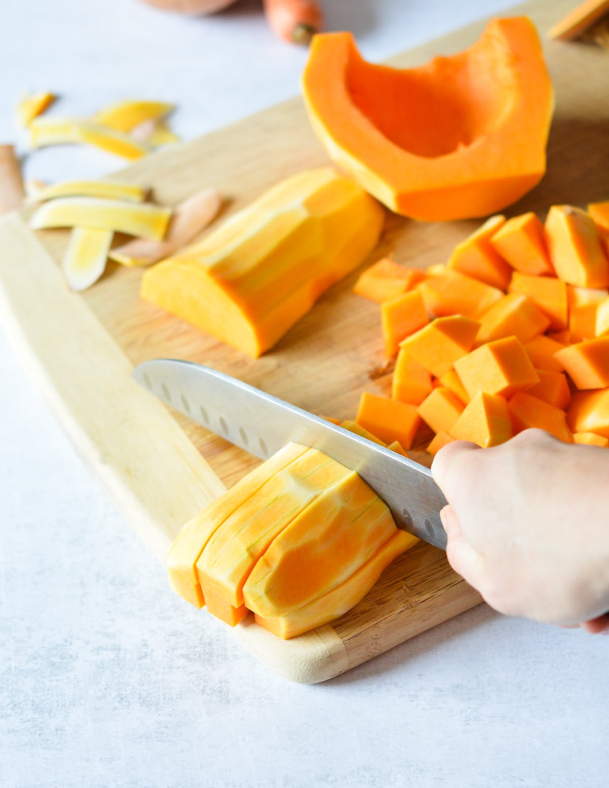 knife cutting butternut squash into chunks.