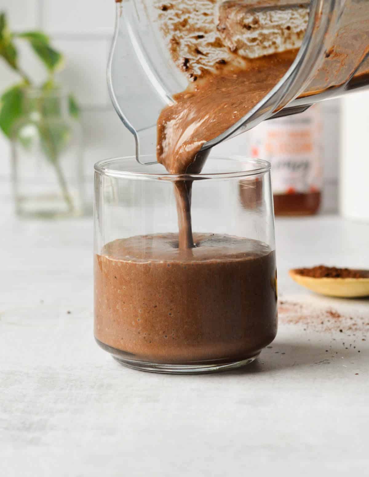pouring chocolate coffee smoothie into a glass.