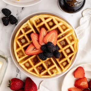 a waffle with strawberries and blackberries on top.