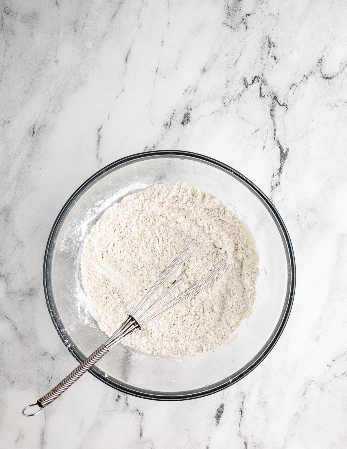 a bowl of gluten-free flour with a whisk in it.
