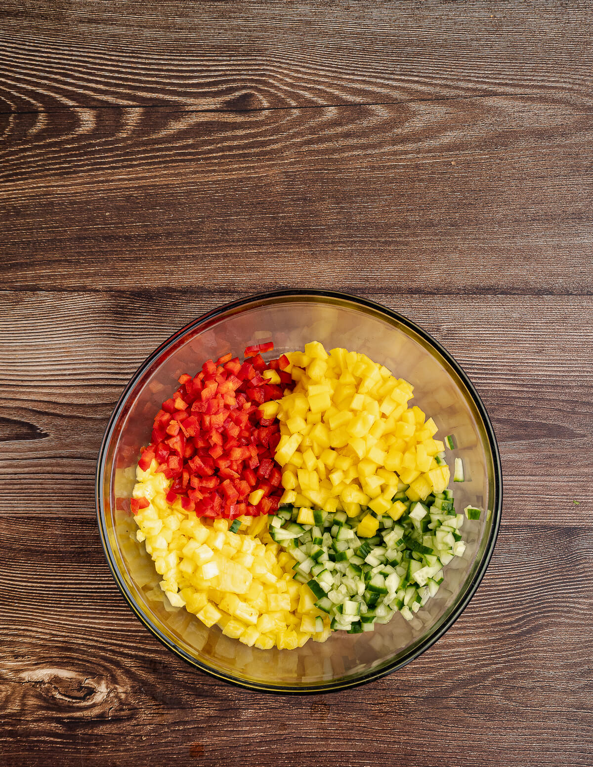 a bowl with diced mango, cucumber, pineapple, and red bell pepper in it.