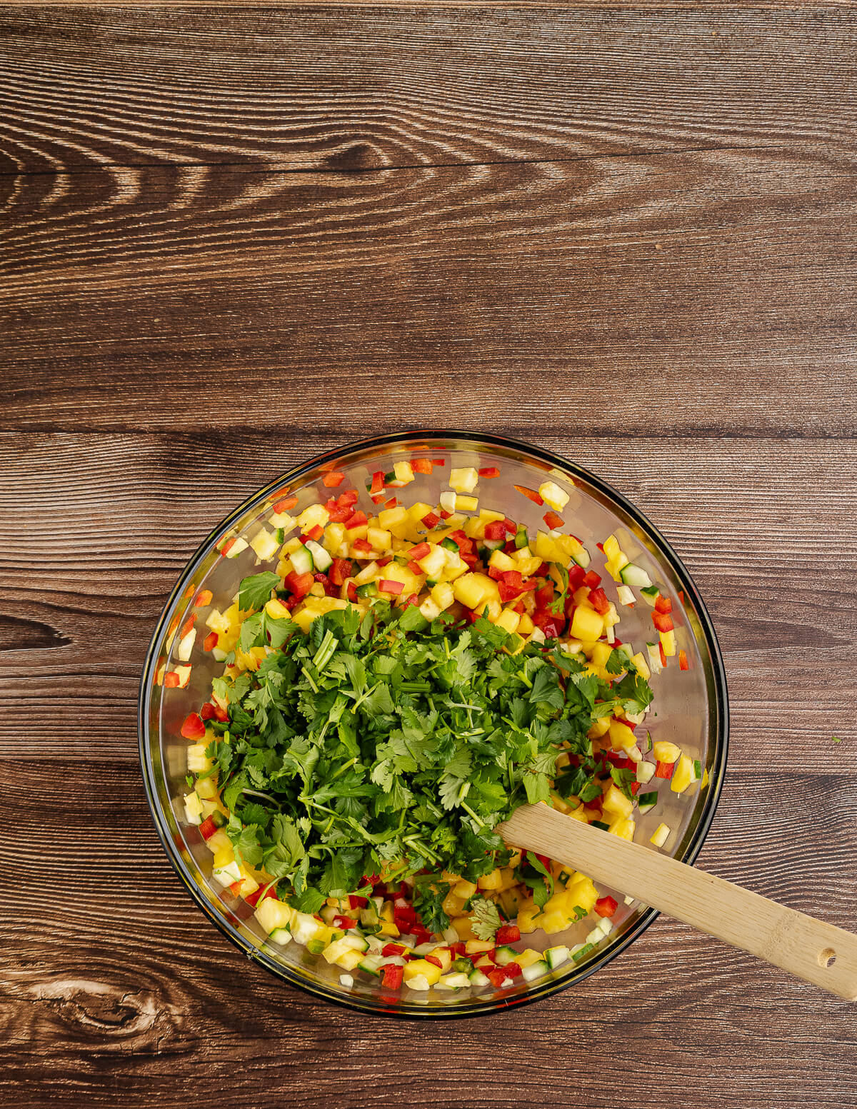 diced pineapple, cucumber, red bell pepper, and mango with cilantro on top.