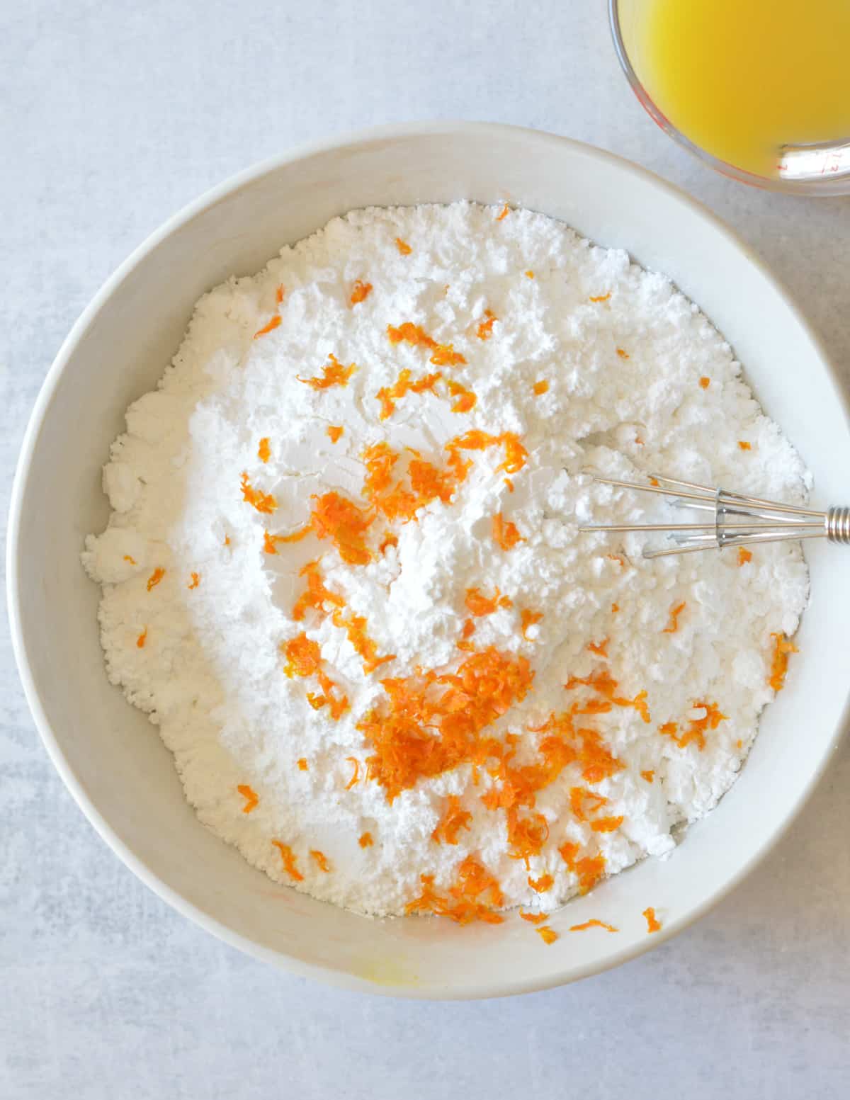a bowl of powdered sugar with orange zest on top.
