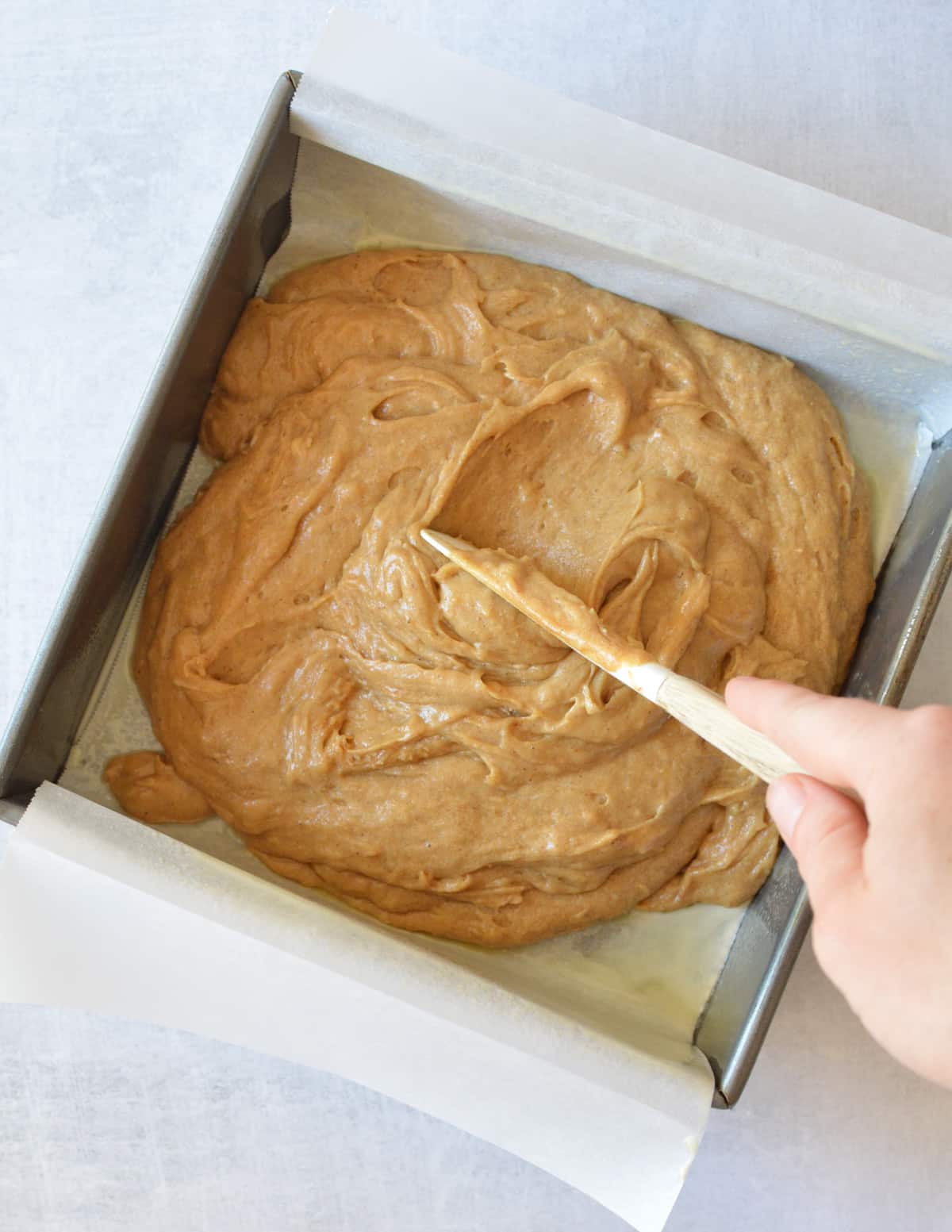 spreading gluten free gingerbread cake batter into a pan.