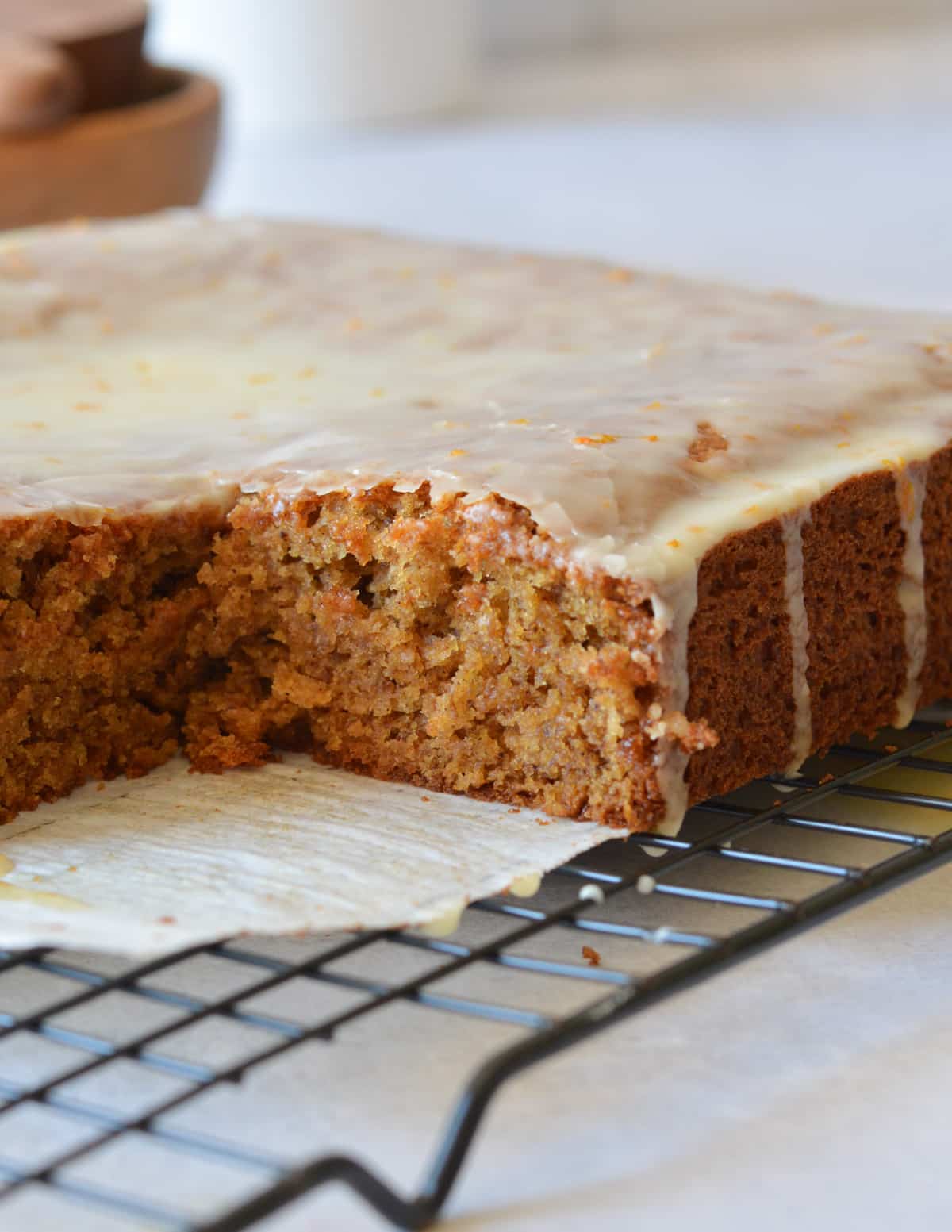gluten free gingerbread cake on a wire rack with a slice cut out of it.