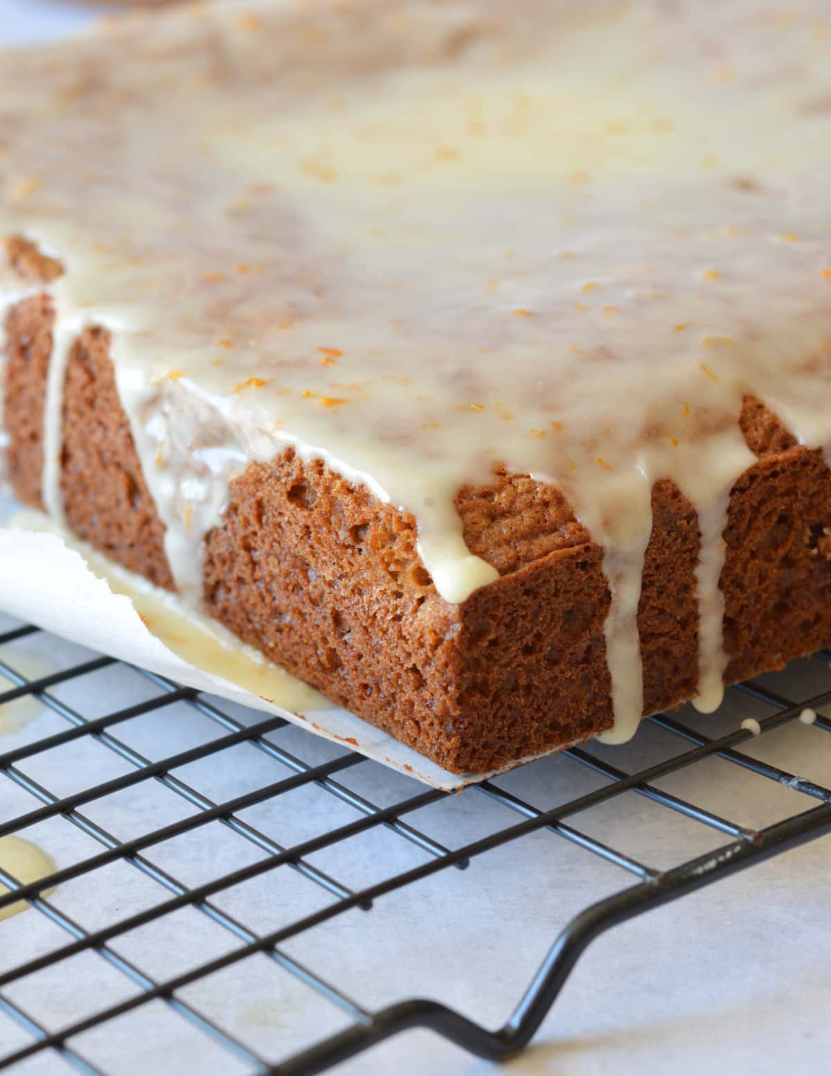 gingerbread cake on a wire rack with orange glaze on top.