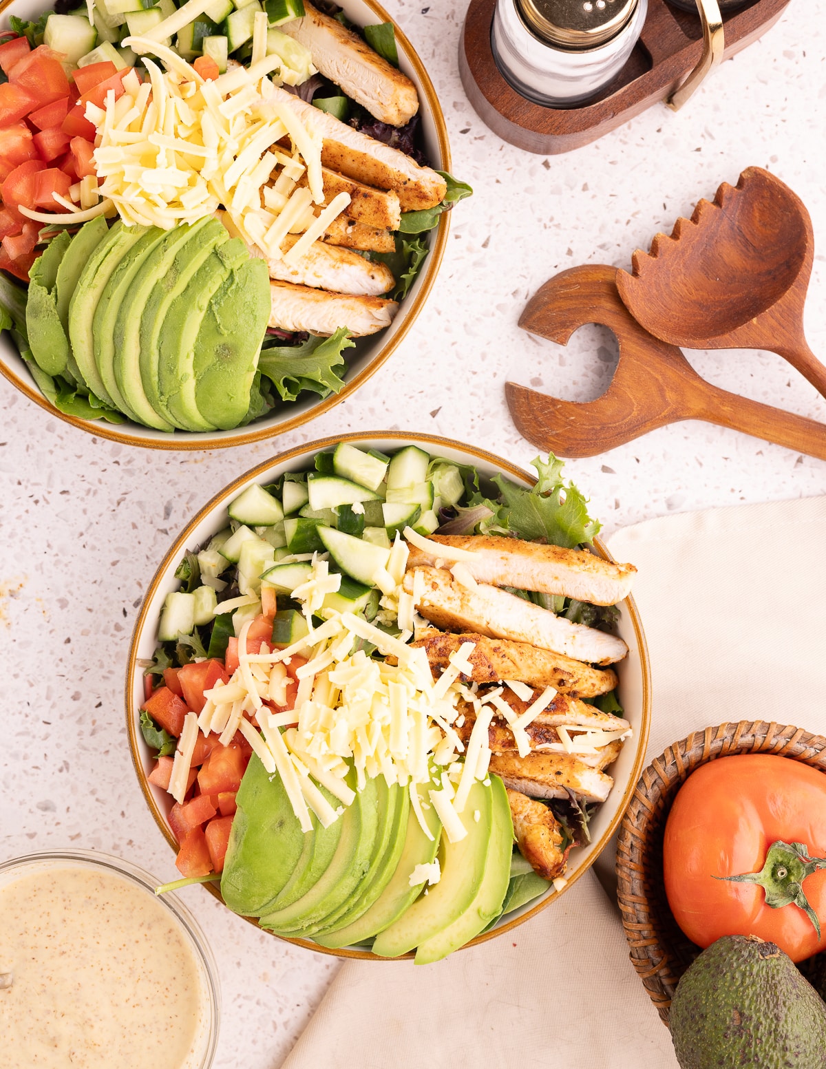 mixed greens salad with avocado, cucumber, tomatoes, shredded cheese, and grilled chicken.