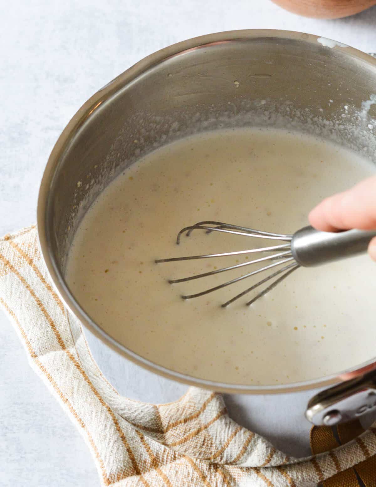 stirring milk and grits in a saucepan with a whisk.