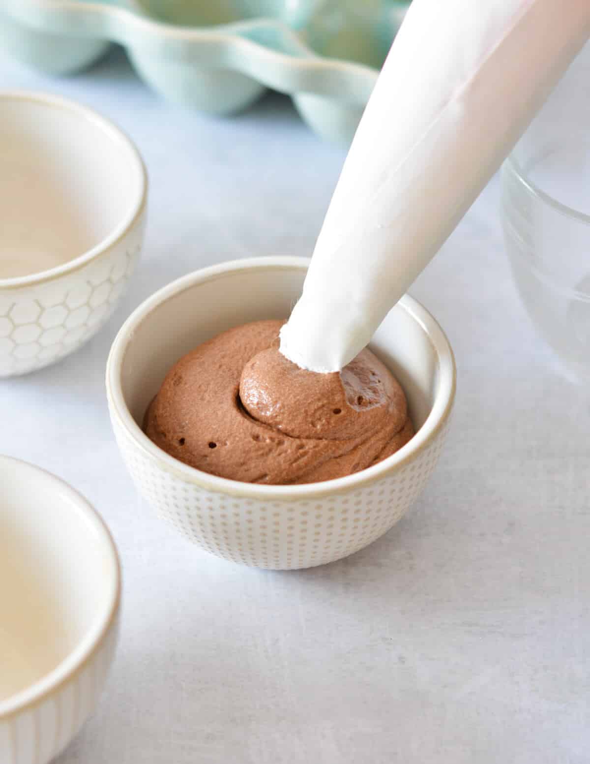 piping chocolate mousse into a small bowl.