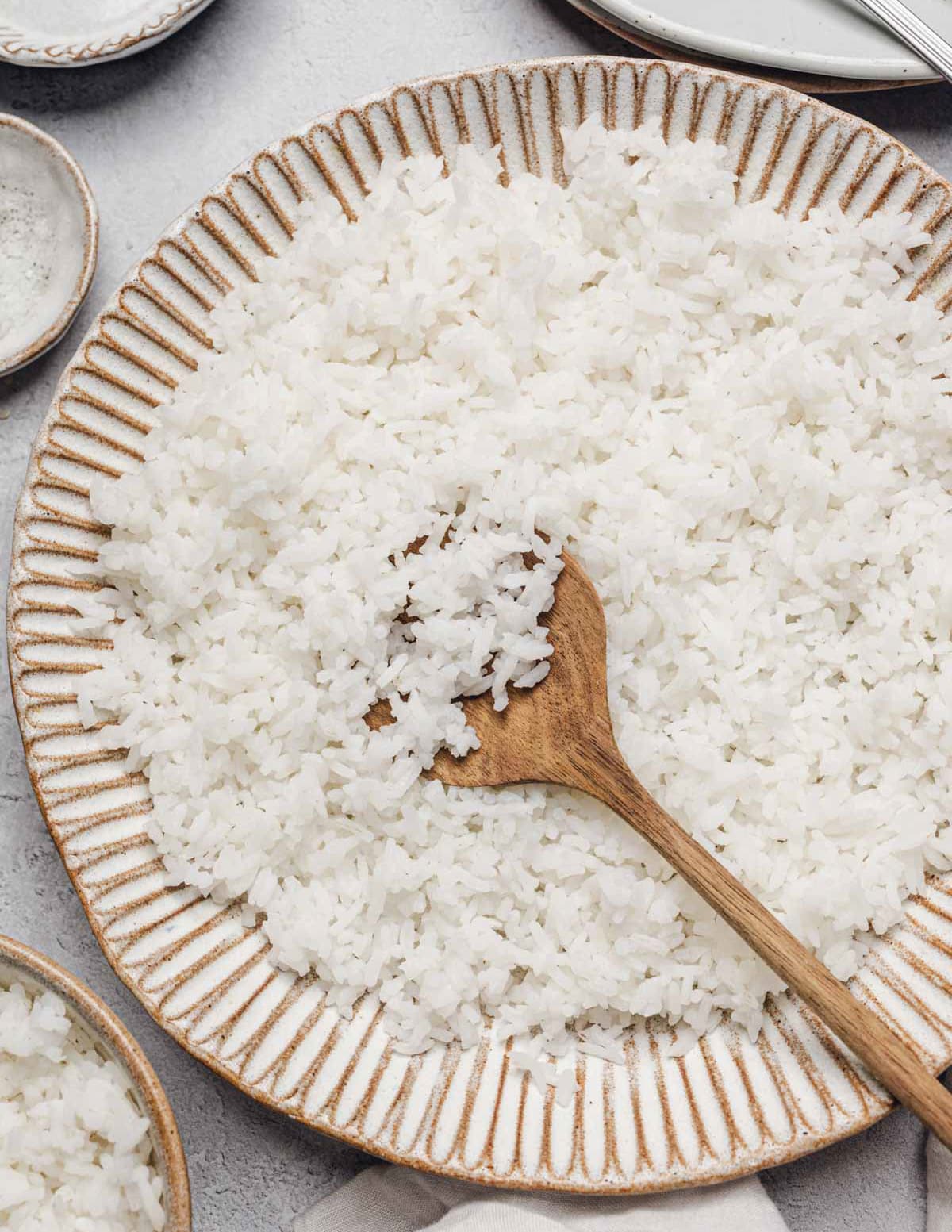 a bowl of white rice with a wooden spoon in it.