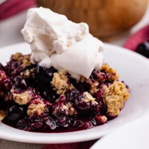 a plate of gluten free blueberry crisp with vanilla ice cream on top.