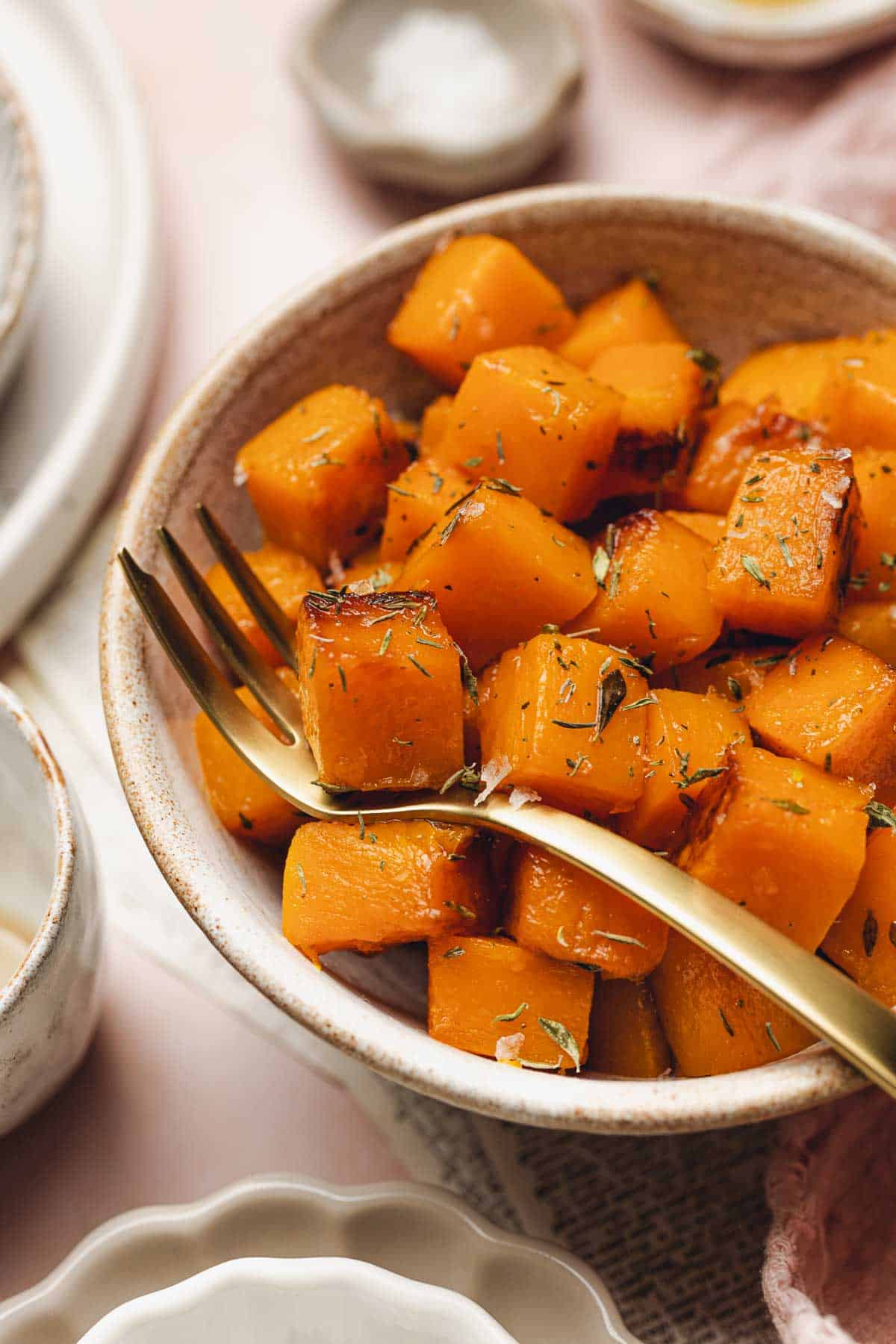a bowl of sauteed butternut squash with a fork in it.