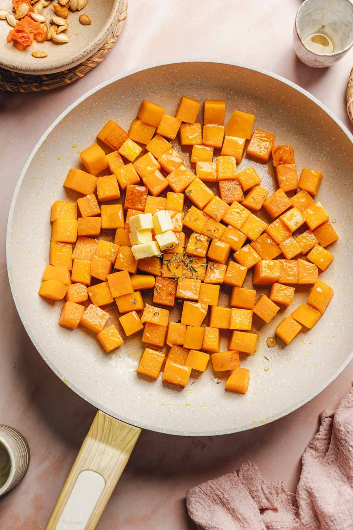 sauteed butternut squash in a skillet with butter on top.