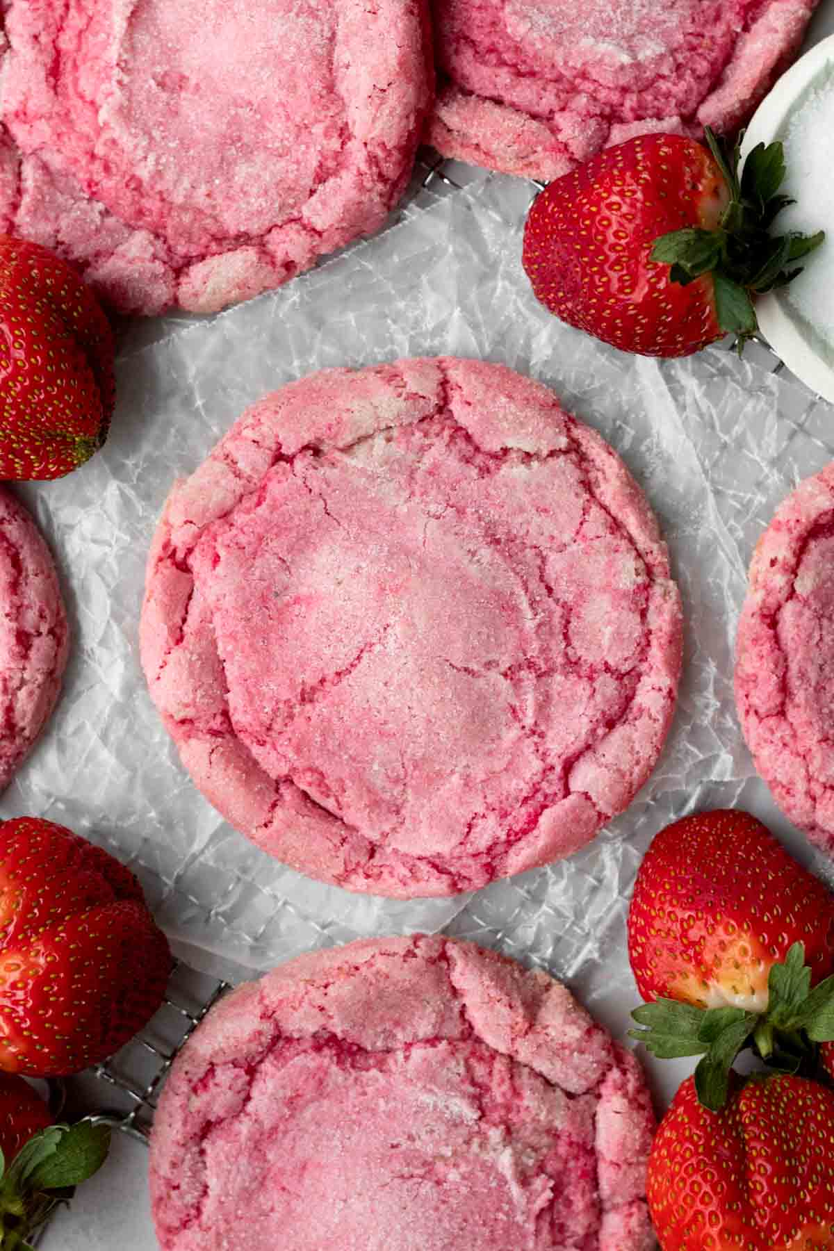 gluten free strawberry cookies on parchment paper next to strawberries. 