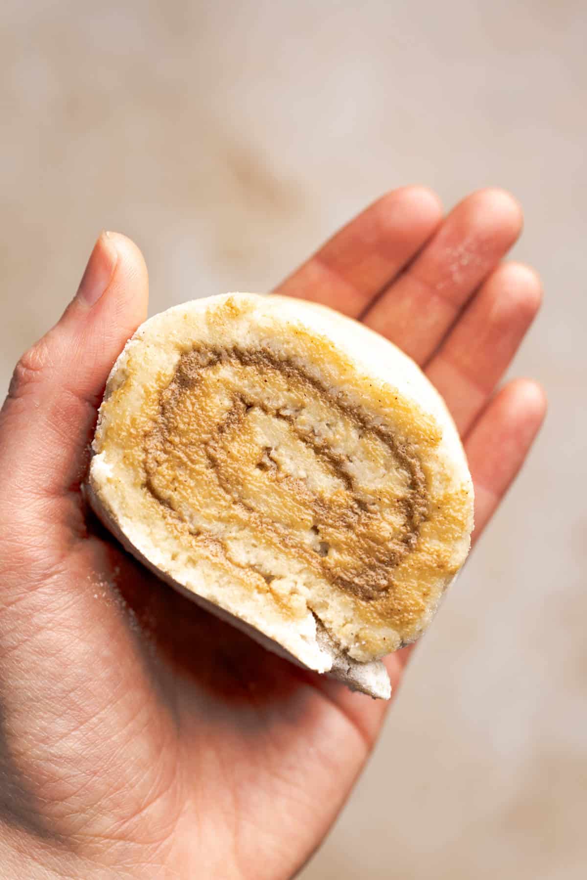 hand holding an unbaked gluten free cinnamon roll.