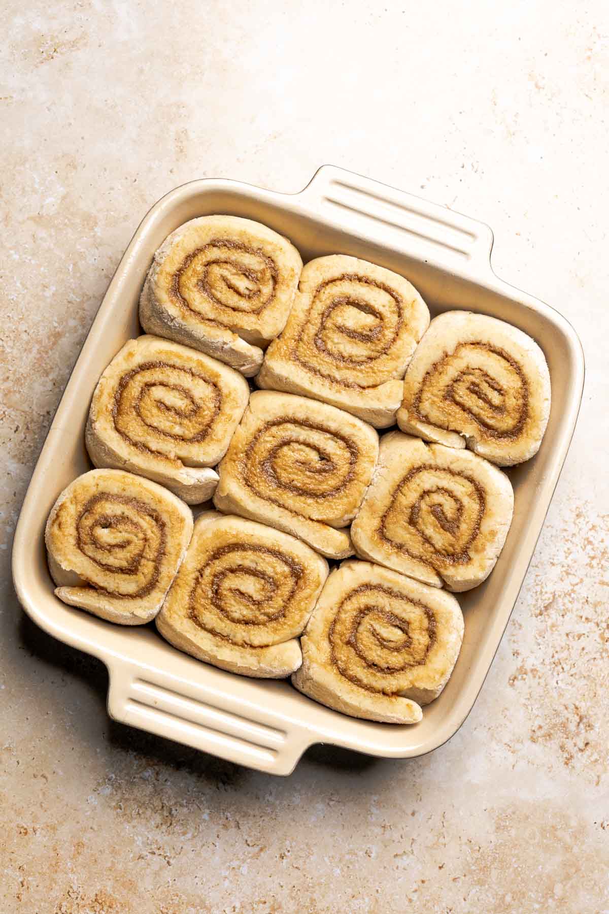 risen cinnamon rolls in a baking dish.
