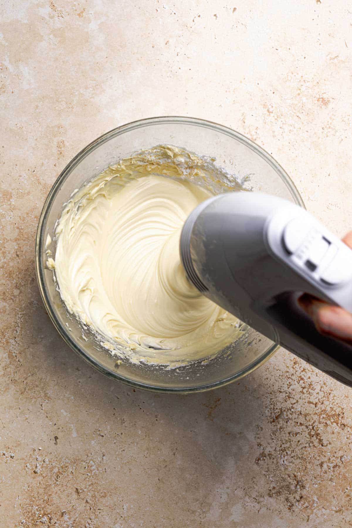 hand mixer mixing cream cheese frosting.