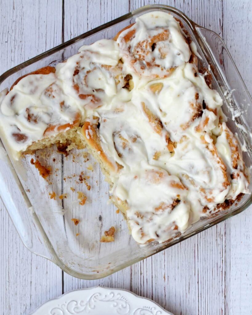 a glass pan of gluten free cinnamon rolls with two missing