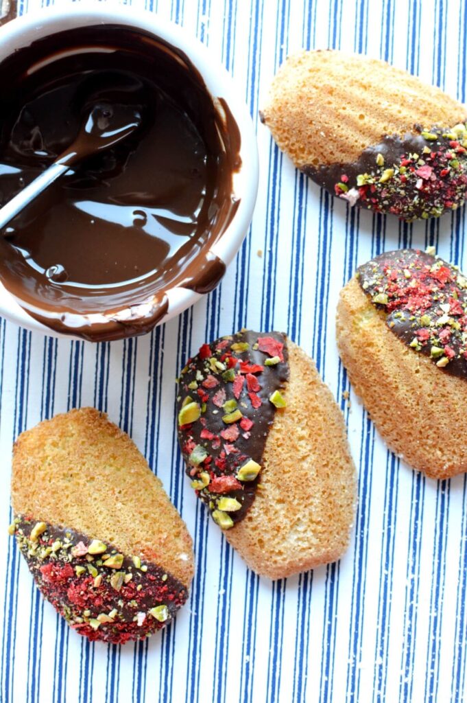 gluten free madeleines dipped in chocolate and topped with pistachios and dried strawberries