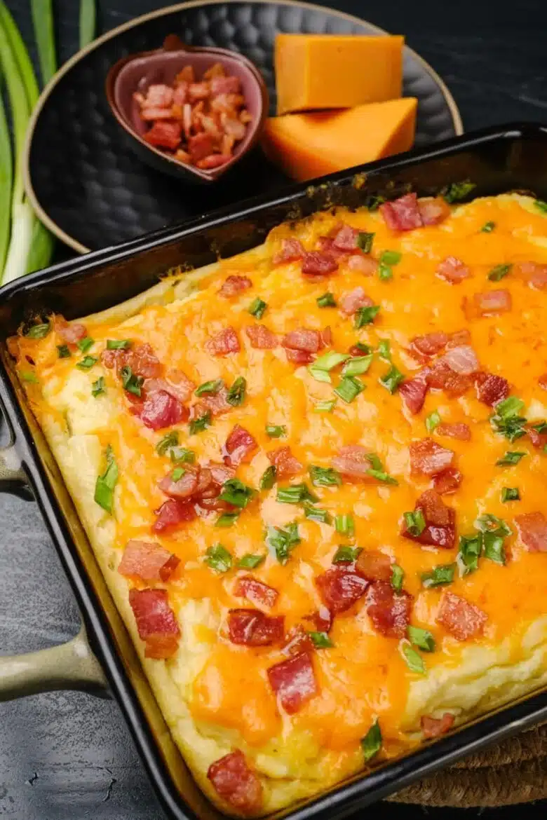 baked mashed potatoes with melted cheese, bacon, and sliced green onions on top. 