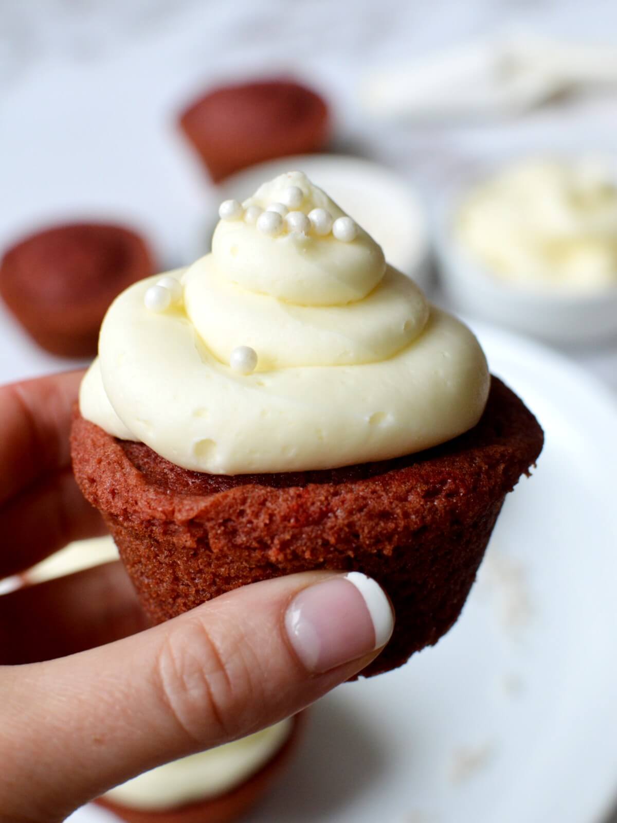 hand holding gluten free red velvet cupcake.