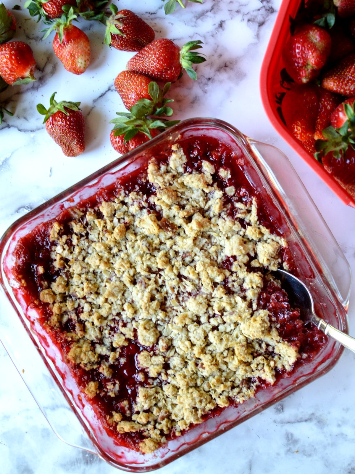 A gluten free strawberry crisp next to fresh strawberries