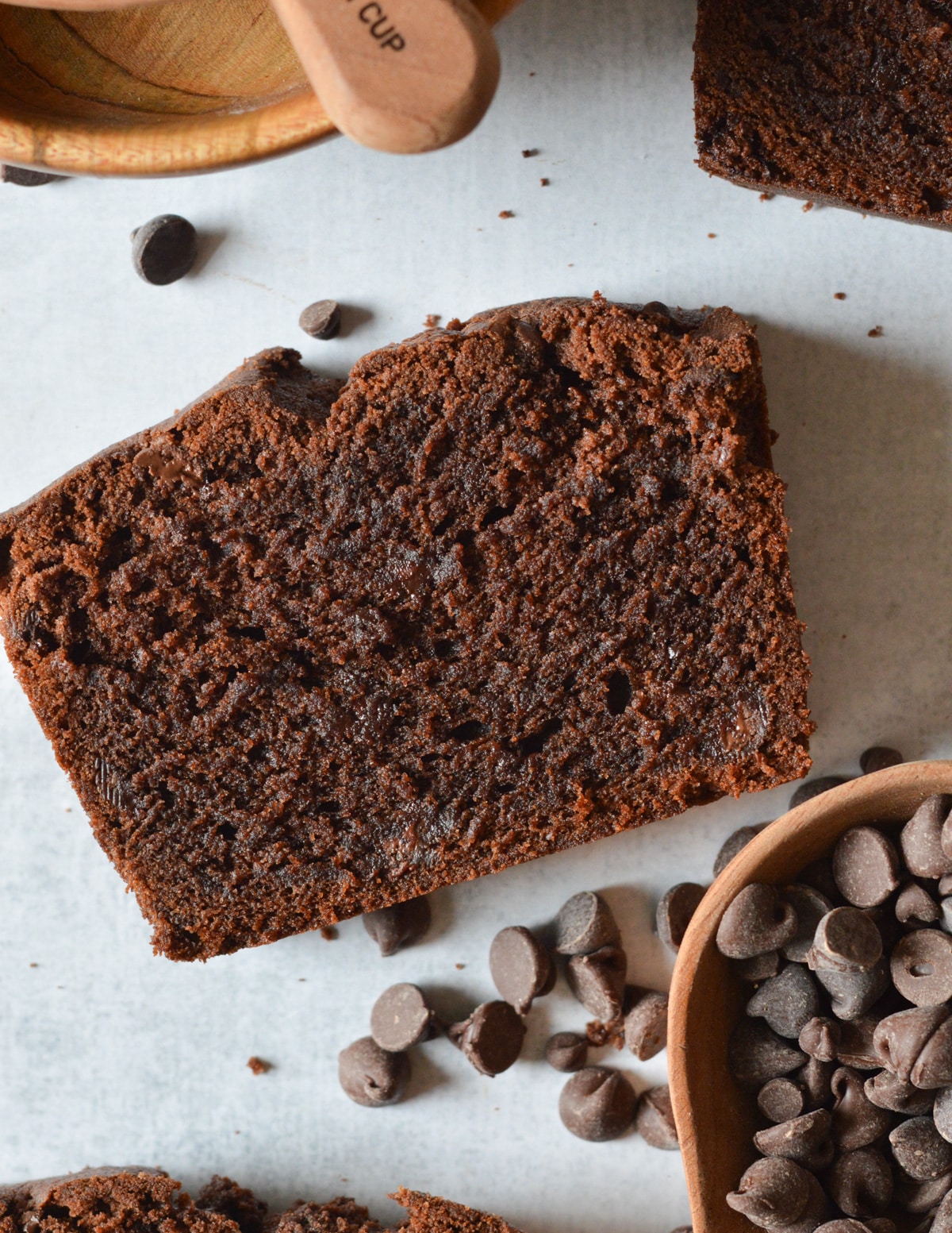 a slice of chocolate pound cake near a bowl of chocolate chips.