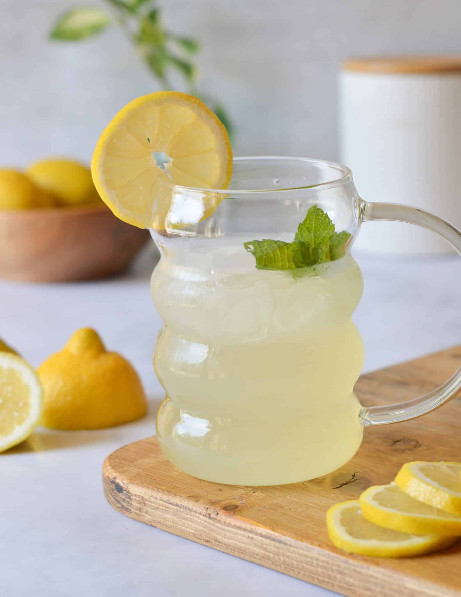 a glass of homemade lemonade with mint and lemons