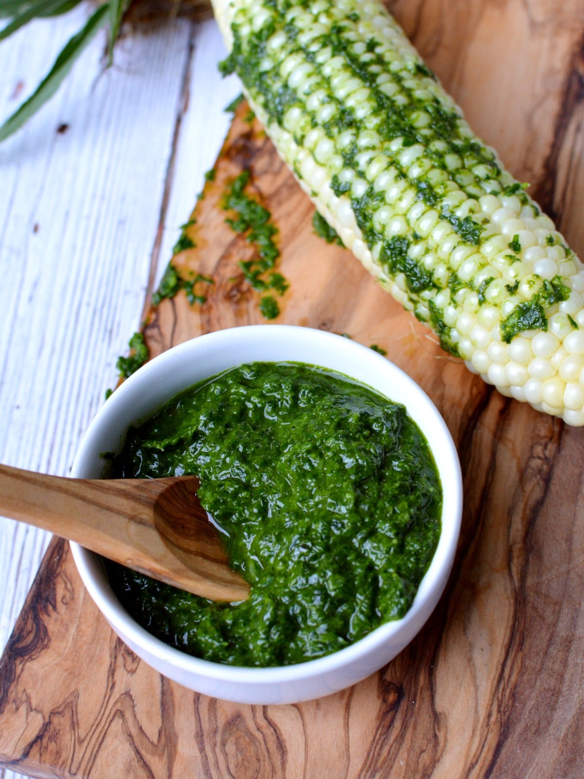 a bowl of basil chimichurri next to corn. 