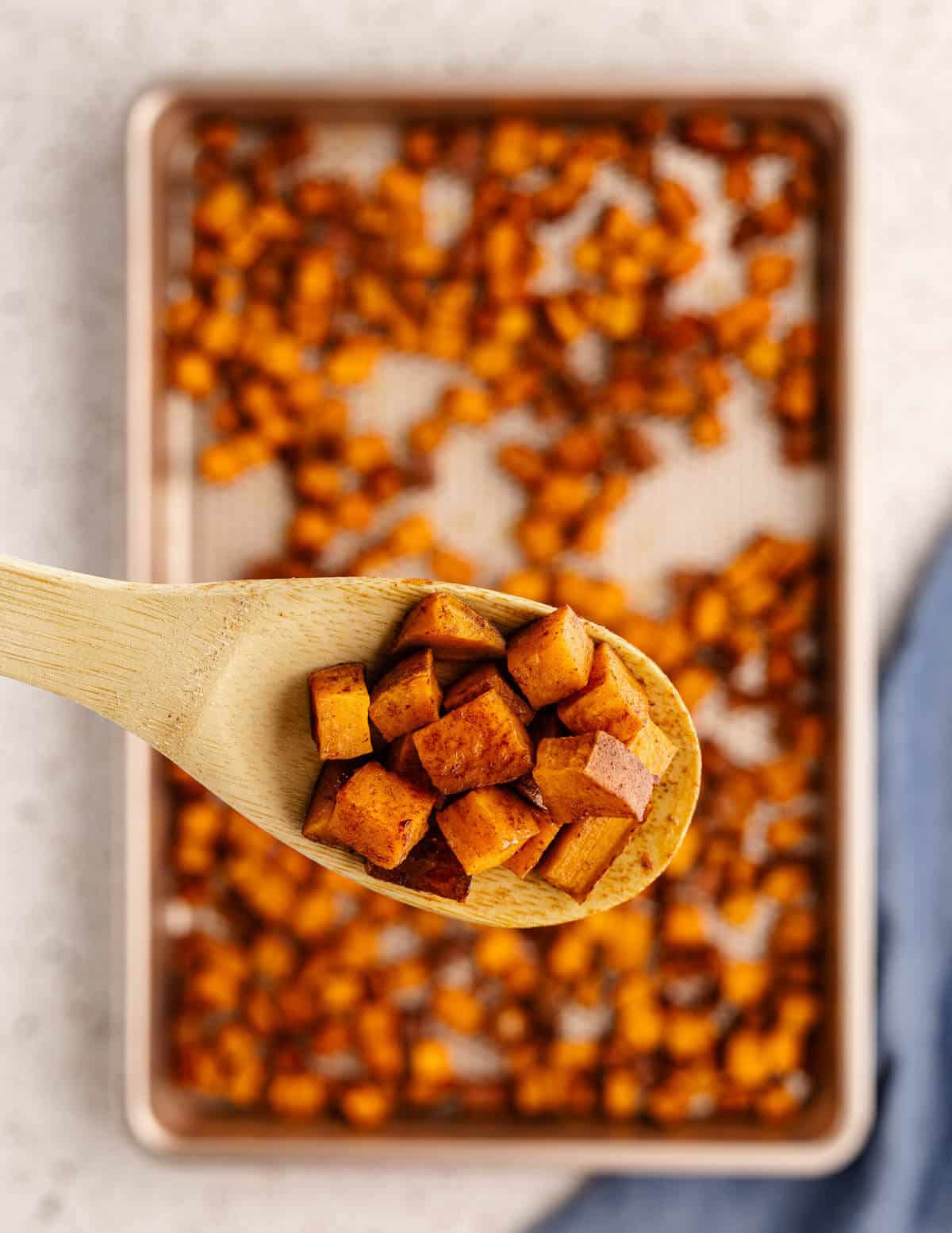 a wooden spoonful of roasted sweet potatoes.