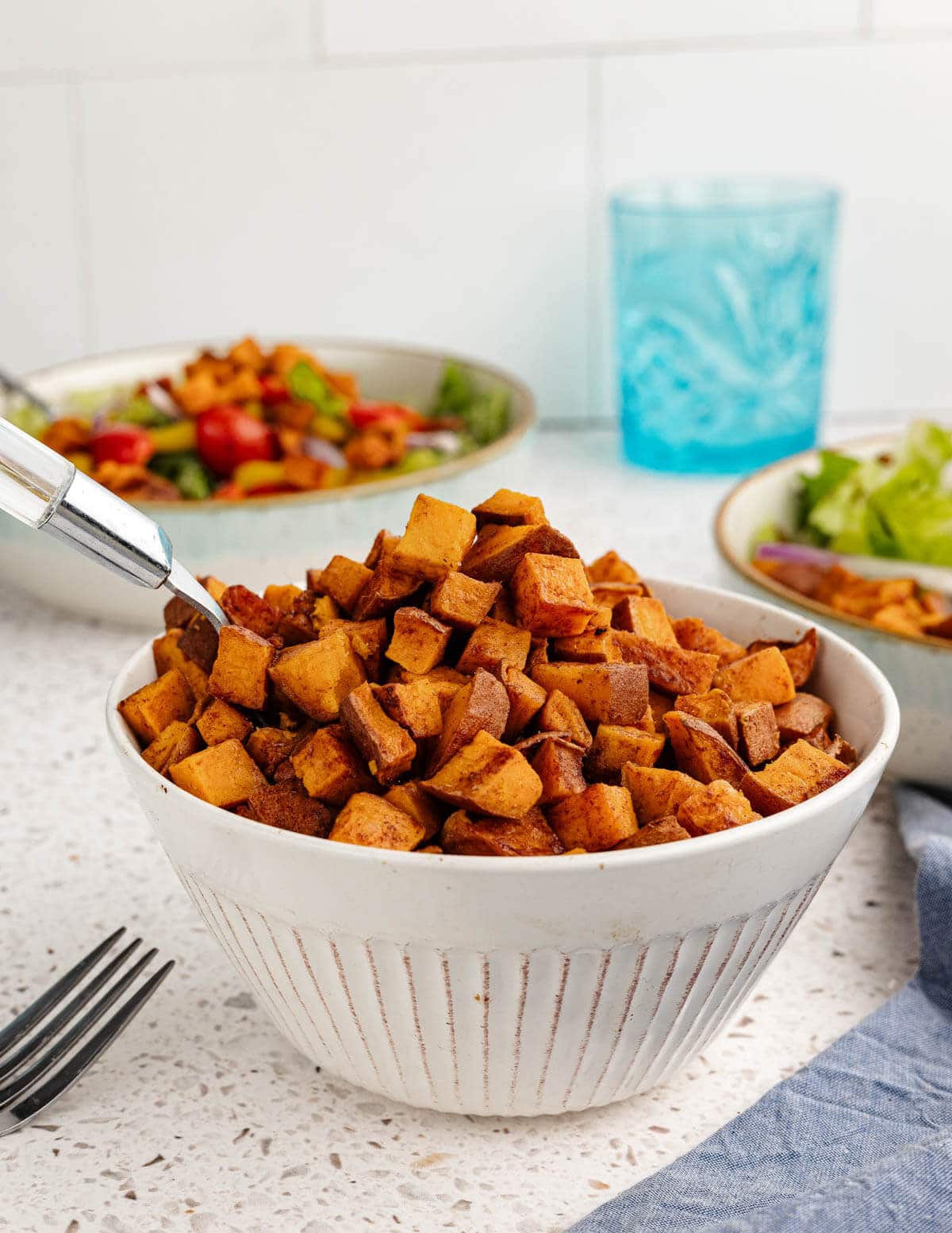 a bowl of roasted sweet potatoes with a spoon in it.
