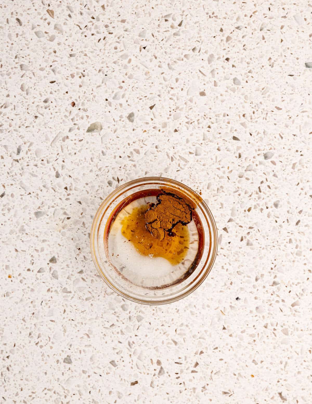 a small glass bowl with coconut oil, maple syrup, and cinnamon in it.