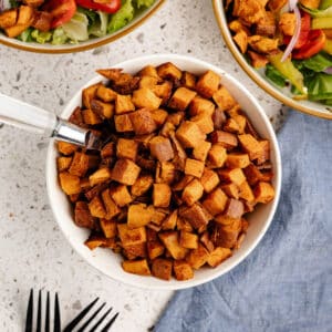 a bowl of roasted sweet potatoes with a spoon in it.