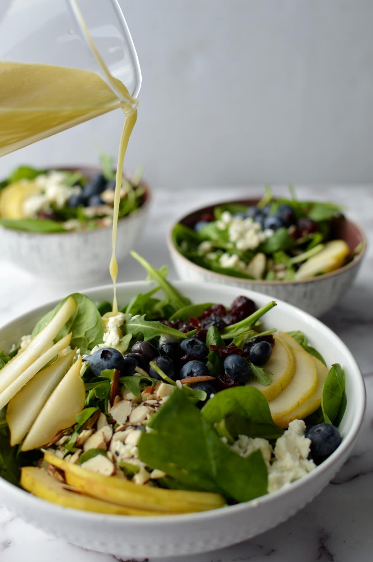 pouring lemon vinaigrette onto spinach salad.