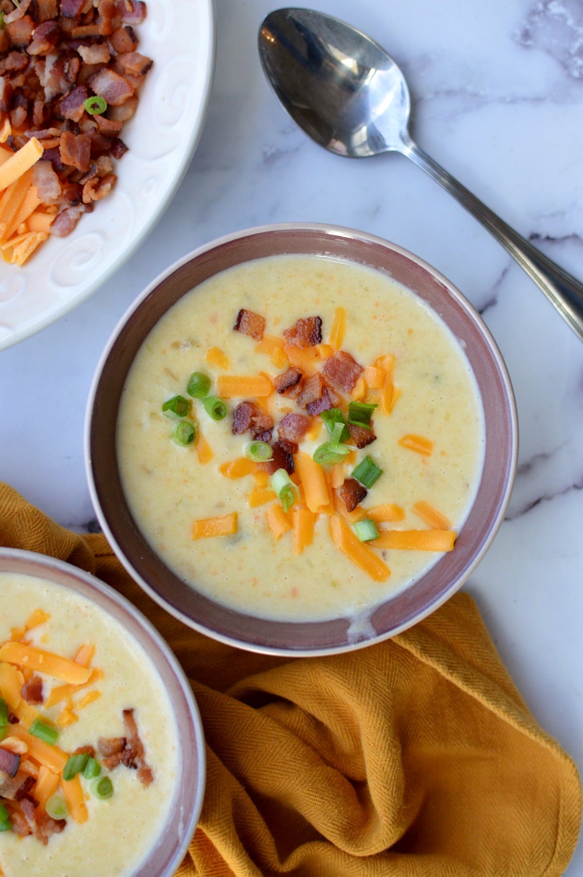 two bowls of potato soup with cheese and bacon