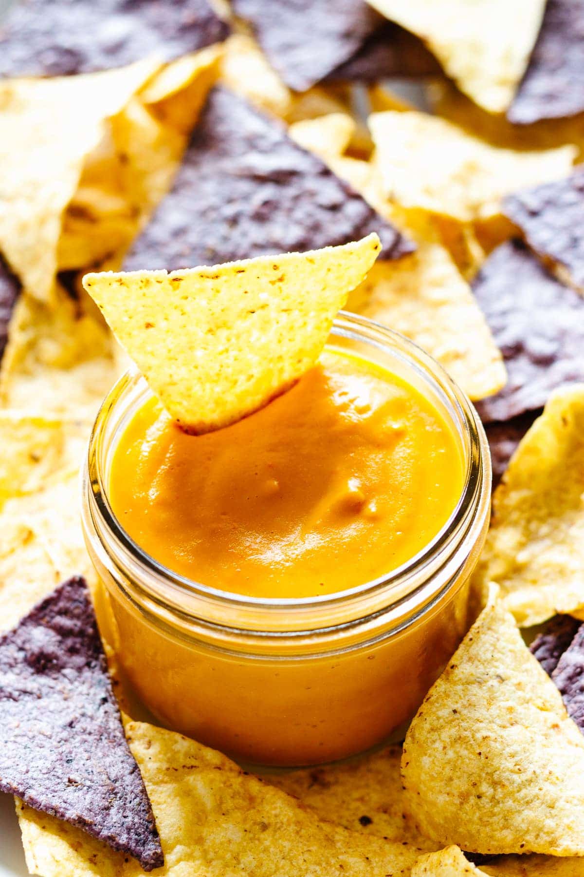 a jar of vegan cheese sauce with tortilla chips