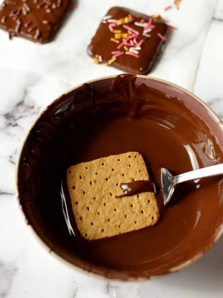 graham cracker in a bowl of melted chocolate