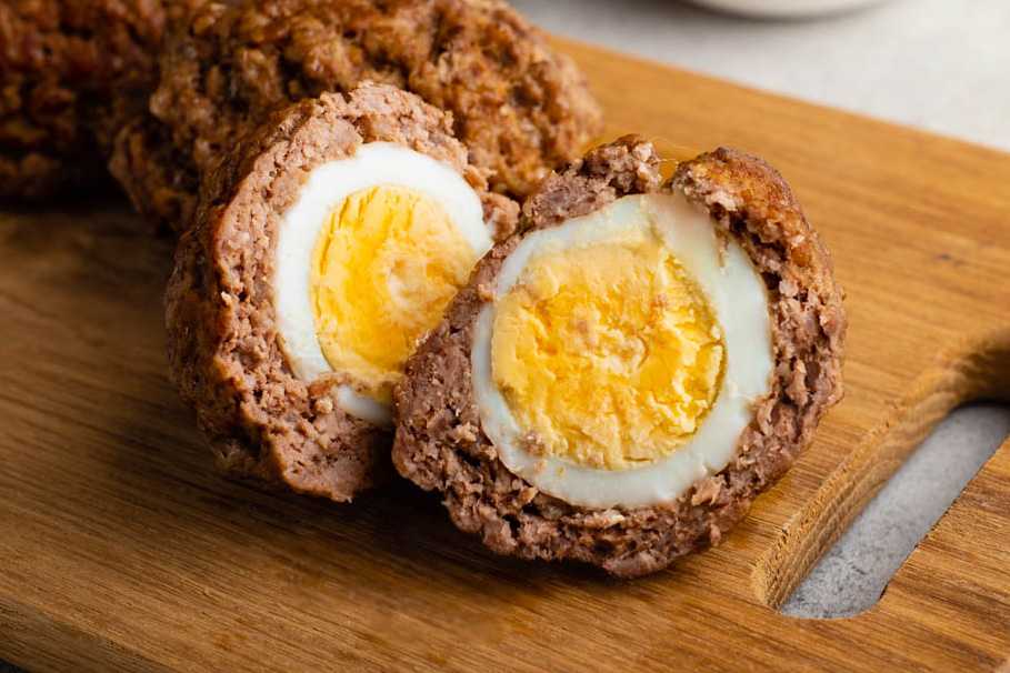 two scotch eggs on a cutting board