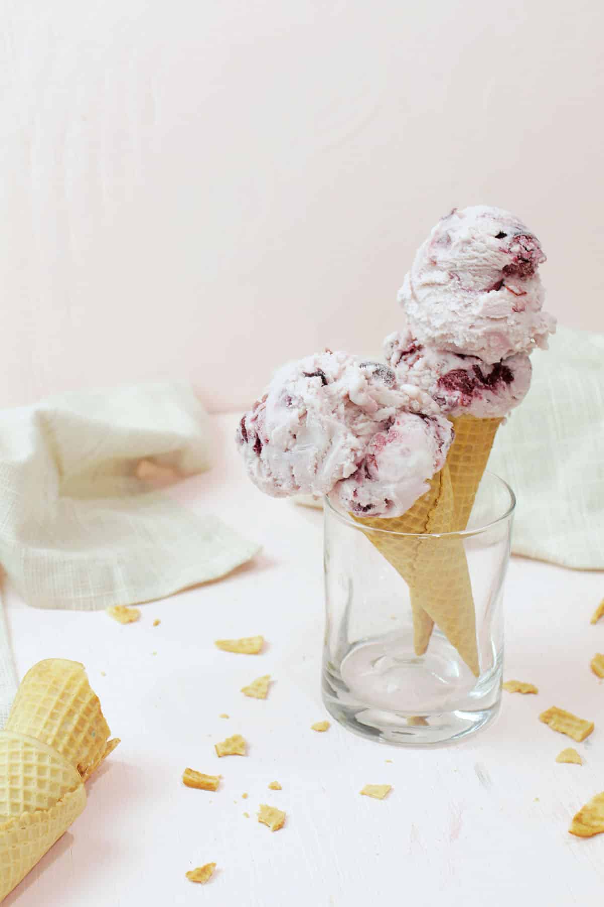 two cones with black cherry ice cream on them