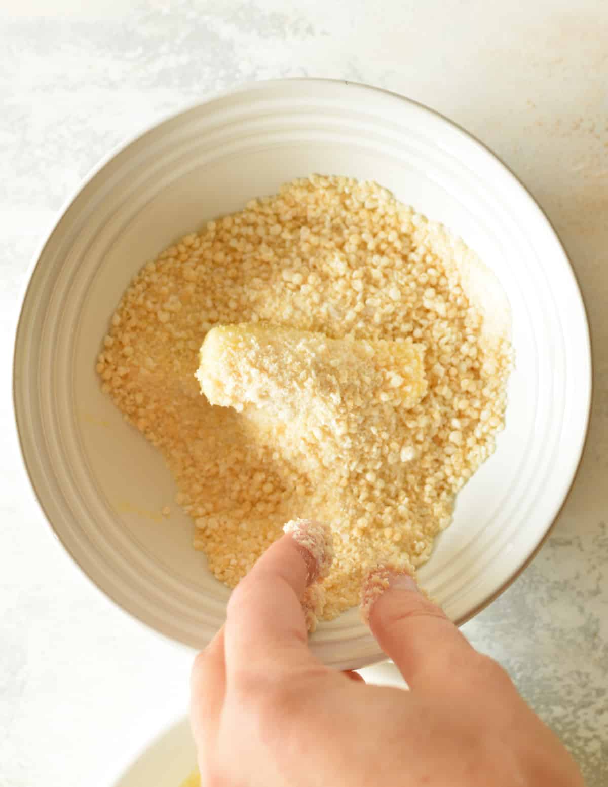 a cheese stick in a bowl of gluten free breadcrumbs