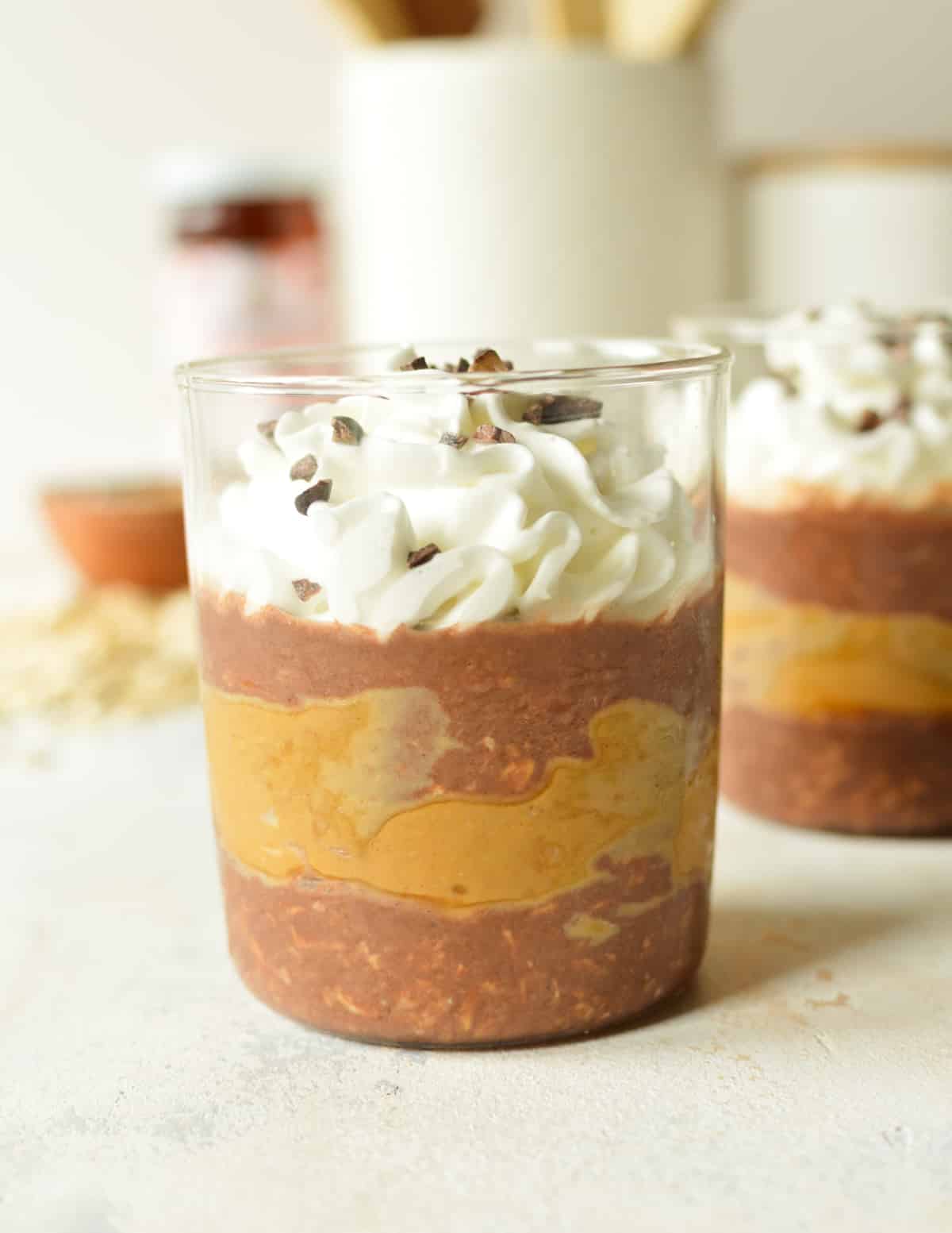 a glass of chocolate and peanut butter oats with whipped cream