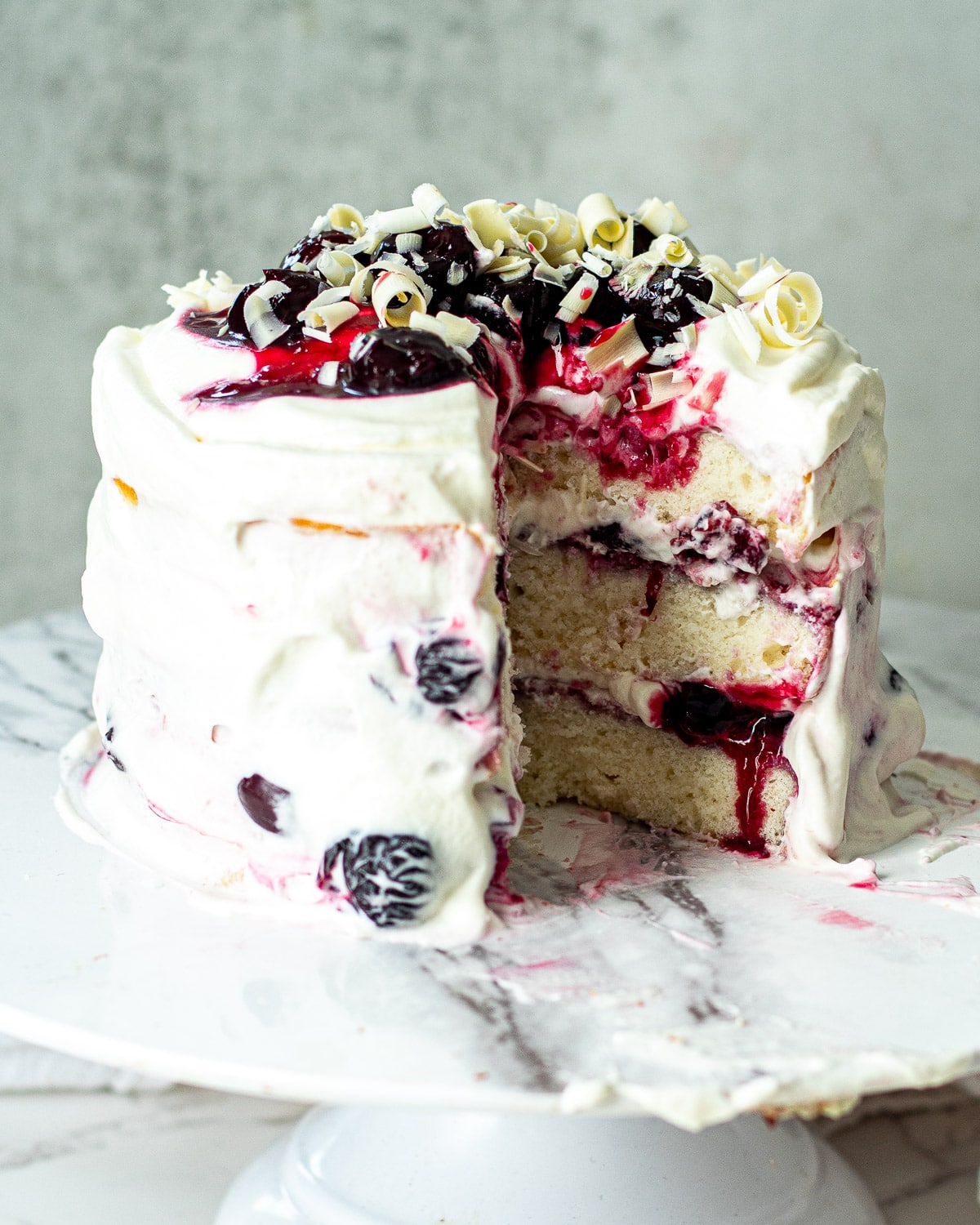 a white forest cake with cherries and white chocolate