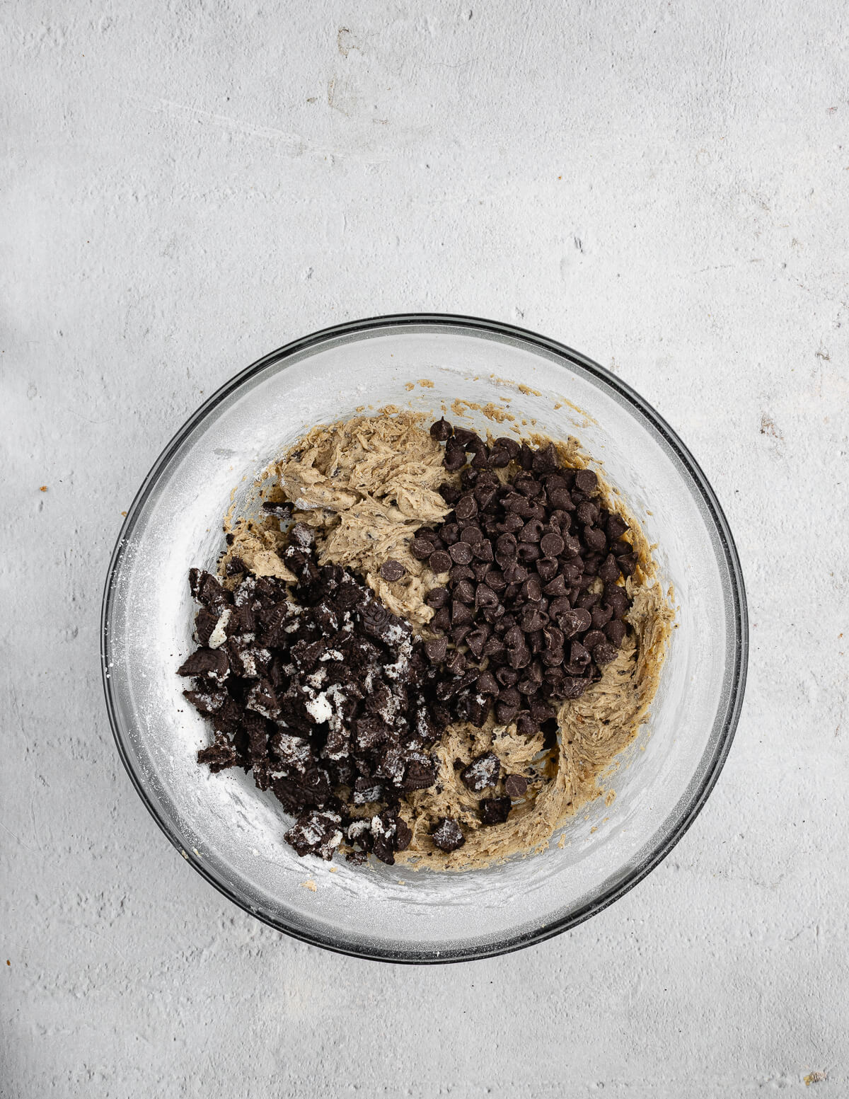 a bowl of cookie dough with Oreo pieces and chocolate chips on top.