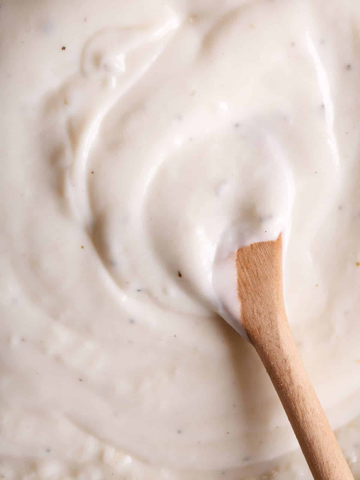 a wooden spoon stirring bechamel sauce