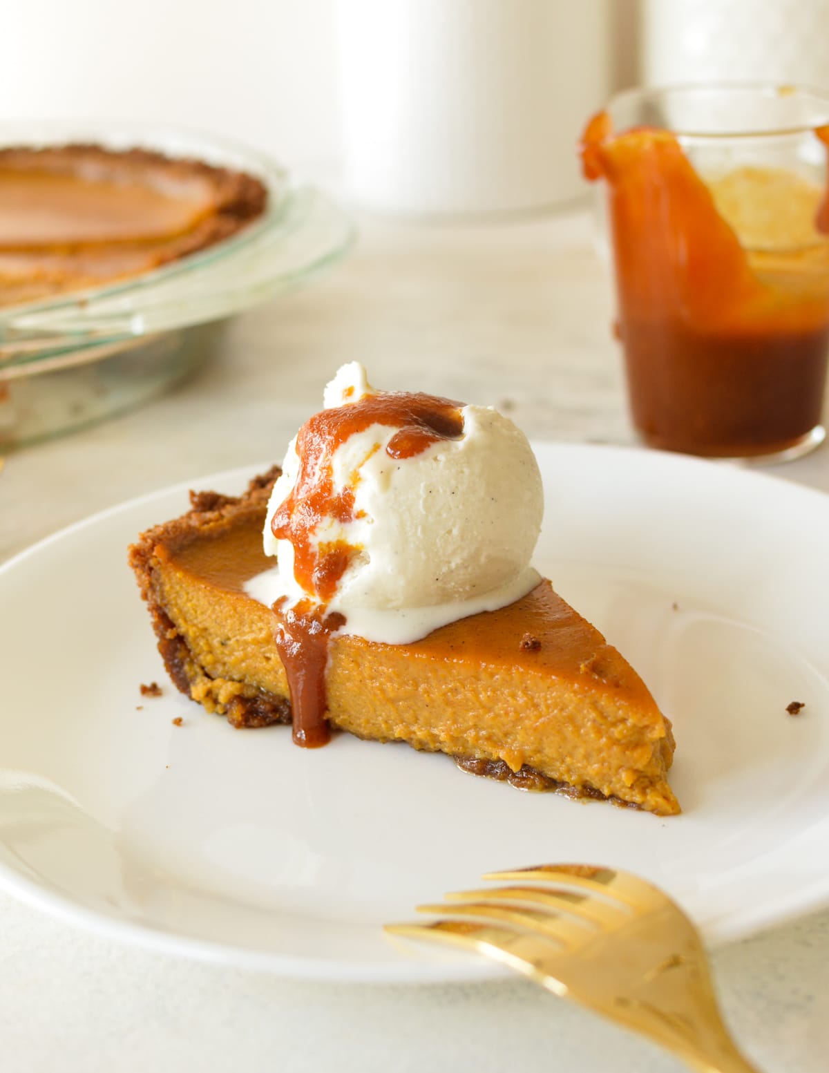 a slice of pumpkin pie with ice cream and caramel