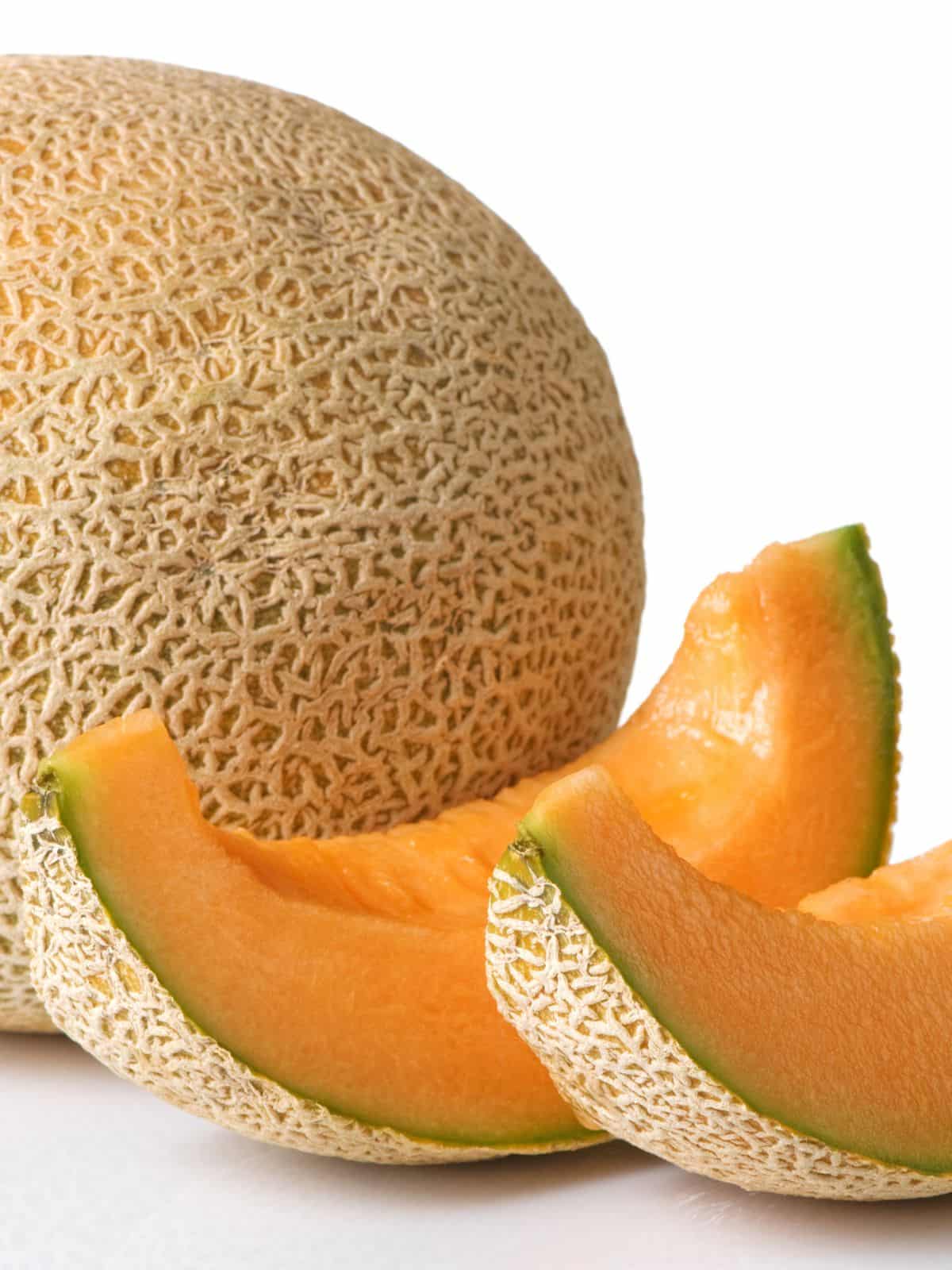 two slices of cantaloupe next to a whole melon.