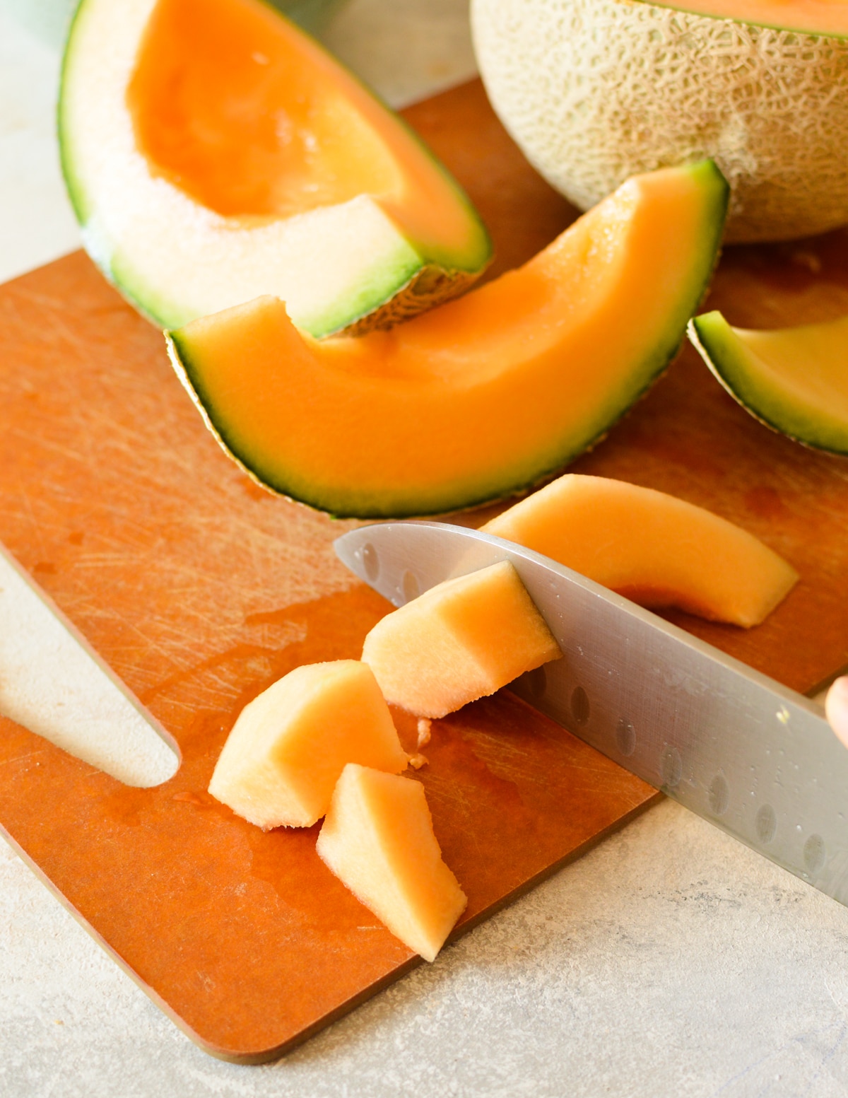knife cutting cantaloupe into chunks.