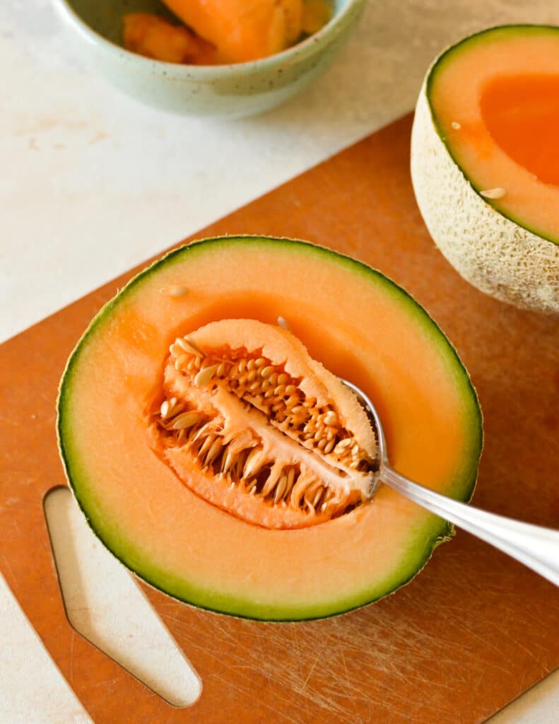 half a cantaloupe with a spoon in it.